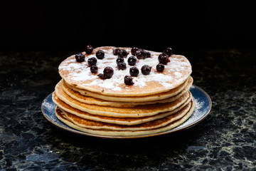 Stack of pancakes with black currant berries and honey.