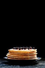 Stack of pancakes with black currant berries and honey.
