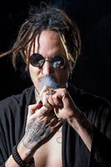 Hippy smoker with dreadlocks in sunglasses and bare chest