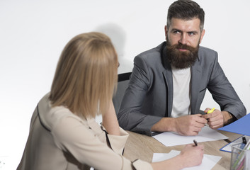 Businessman work on business plan with businesswoman. Bearded man sit at desk with woman, back view. Man with beard and mustache on serious face. Business meeting concept. Busy day in office
