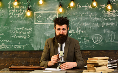 Bearded man work with microscope. Man with beard and mustache in school. Scientist make research on chalkboard. Businessman with glasses and optical instrument at desk. Science and study