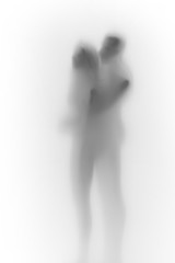 Beautiful couple together hug each-other, body silhouette behind a white curtain