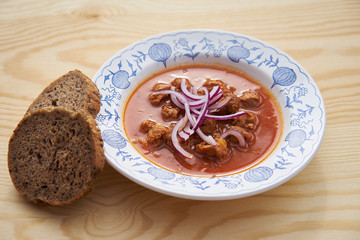 Vegetarian or vegan food or meal made from soya chunks in traditional goulash style with choped red onion served on rustic plate with wholecorn bread as a side dish. 