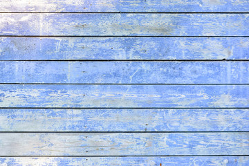 The wall is made of flat horizontally painted boards painted with blue paint. Old faded coating...