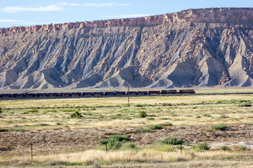 Freight Train Pulling Its Cars Through The Massive Landscape Of Utah