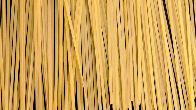 Stop motion top view of raw spaghetti on a black table. Close up of pasta background time lapse