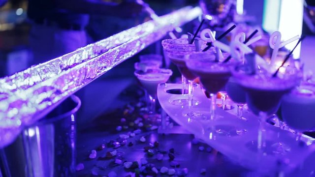 The fiery trail and a table Laden with cocktails at the party. Close-up of hands the bartender a vast array of cocktails.