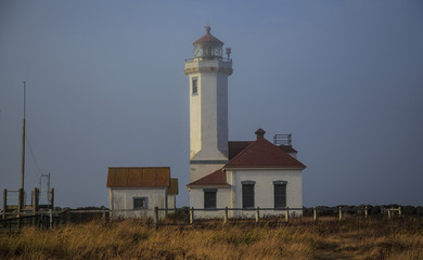 Fototapeta na wymiar Lighthouse and buildings on misty day