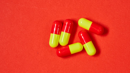 Pills spilling out of pill bottle on red. Top view with copy space. 