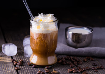 Ice coffee in a small glass on dark natural desk.