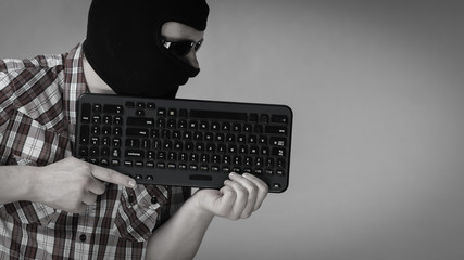 Man wearing balaclava holding keyboard
