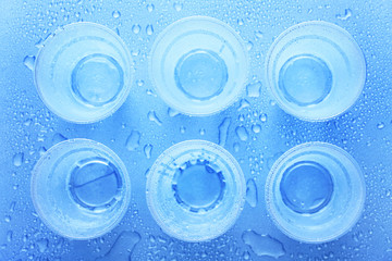 Disposable plastic cups with water drops on a blue background