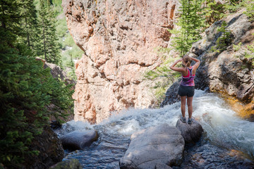 A woman standing near the edge of Booth Falls in Vail, Colorado. 