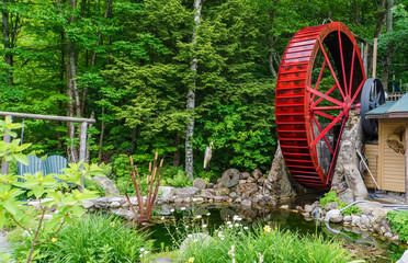 bright red historic water wheel turning slowly in garden 