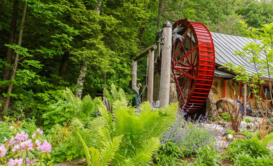 bright red historic water wheel turning slowly in garden 