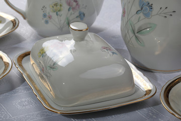 White porcelain butter dish with painted flowers on a tablecloth