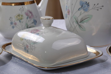 White porcelain butter dish with painted flowers on a tablecloth