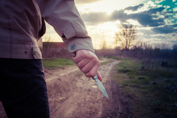 Man with a knife hidden behind her back in the park.