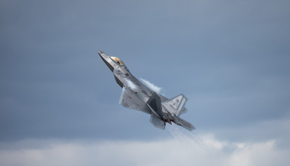 F-22 Raptor in a  high G maneuver, with condensation trails forming  above the wing and the hot jet...
