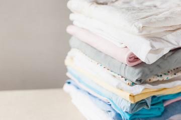 A stack of clean folded cotton clothes ready for ironing. Everyday homework concept. Soft focus.