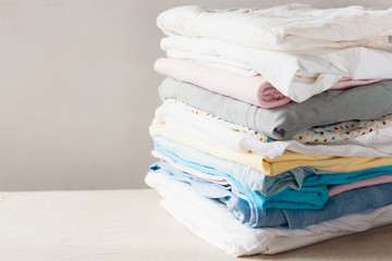 A stack of clean folded cotton clothes ready for ironing. Everyday homework concept. Soft focus.