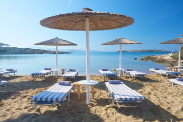 Umbrellas with sunbeds on beautiful sandy Santa Maria beach with turquoise sea water, Paros island,...