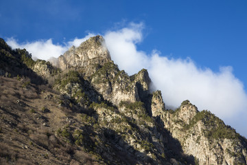 Горный пейзаж. Вершины в белых облаках, Красивый вид на живописное ущелье, панорама с высокими горами. Природа Северного Кавказа, отдых в горах