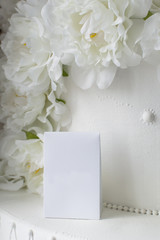 White gift wrap on a background of decorative artificial flowers.