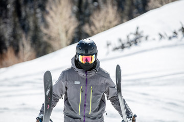 Fototapeta na wymiar Skier Walking Carrying His Skis And Wearing Goggles