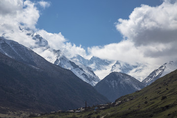 Fototapeta premium Горный пейзаж. Вершины в белых облаках, Красивый вид на живописное ущелье, панорама с высокими горами. Природа Северного Кавказа, отдых в горах