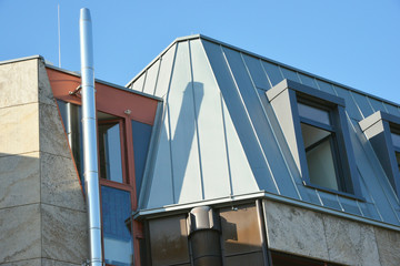 Modernes Stehfalz-Metalldach mit Dachfenster, Dachrinne und Edelstahl-Schornstein