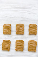 Peanut butter toasts on a white wooden table, top view. Copy space.