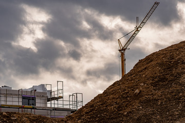 Baustelle in einem Neubaugebiet und Kran hinter einem Erdhügel