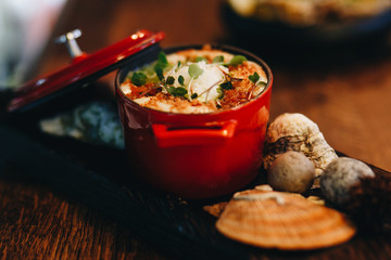hot julienne with seafood in a red pot.