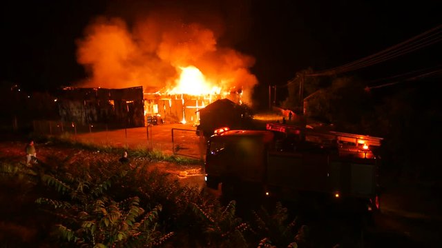 People Watching A House Fire Burning With Firetrucks