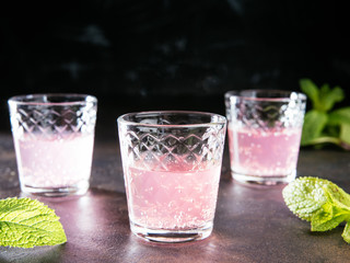 Homemade Strawberry liqueur on a metal table. Alcoholic fruit cocktail shots in a glasses