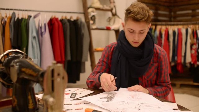 Fashion designer is working on a new collection , making sketches
