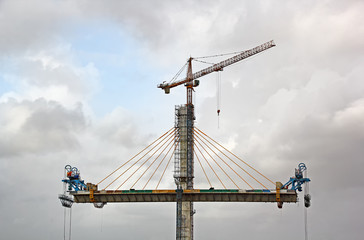 Fototapeta premium Erecting cable stayed bridge progressing on two sides of the tall central concrete pier using tower crane for the third bridge over Mandovi River in Goa, India
