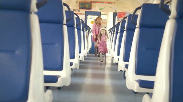 Cheerful little girl with her mom walks into the empty train car