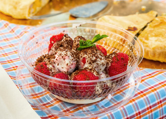 Fresh strawberries with chocolate covered ice cream with a mint leaf on the table with homemade pies