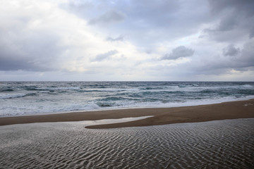 Water ripples on the beach under early morning clouds
