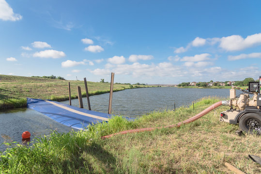 Close-up inflatable dam and industrial pump to diverting water. Inflated barrier at civil engineering projects in Irving, Texas, USA. Water filled cylindrical tubes rubber, grade geo-textile material