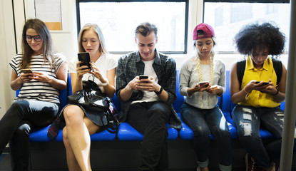 Group of young adult friends using smartphones in the subway