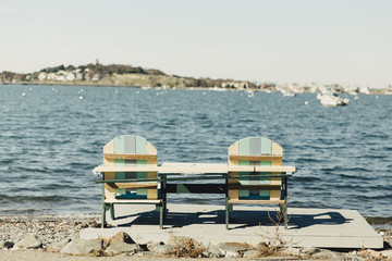 two wooden chairs by the sea. Adirondack chairs on the beach