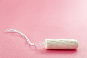 Menstrual cycle, feminine care, menstruation and intimate products concept with internal tampon isolated on pink background with copy space