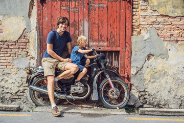 Dad and son on an old motorcycle. Penang