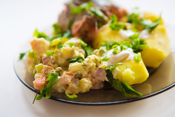 Fried meat with potato salad, greens seasoning white sauce, on a white plate. Clipping path.