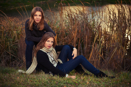 Two young fashion girls in black pullover and dark blue jeans outdoor