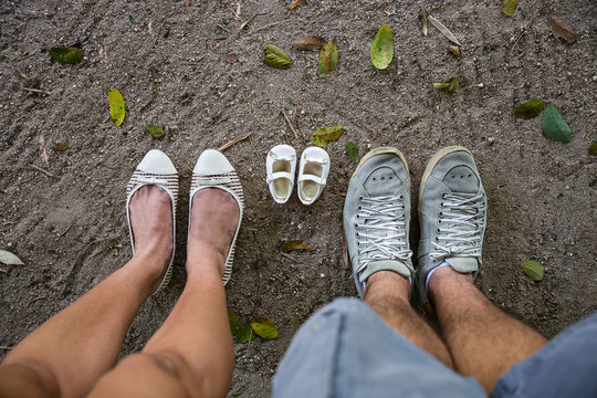 Empty Baby Girl Shoes Between Parents Shoes On Sand