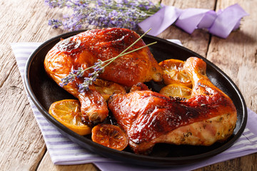 Delicious food: grilled glazed chicken legs with lavender honey and lemon close-up on a plate. horizontal